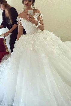 a woman in a white wedding dress taking a selfie with her cell phone while standing next to a red couch