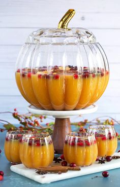 several glasses filled with liquid sitting on top of a white tray next to some fruit