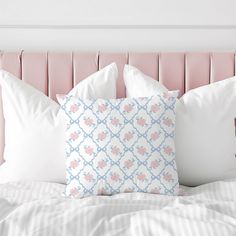 a bed with white pillows and pink headboard, along with two decorative throw pillows