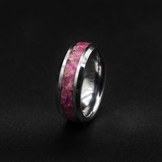 a wedding band with pink and white marble inlaying the center, on a black background