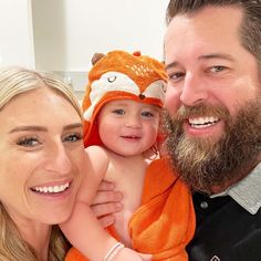 a man with a beard holding a baby in his arms and smiling at the camera