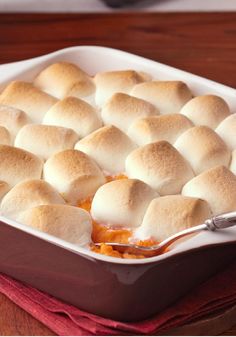 a casserole dish with marshmallows in it on a wooden table