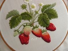 a close up of a embroidery on a white cloth with strawberries and daisies