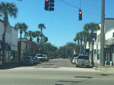 the traffic light is red at an intersection with palm trees on both sides of the street