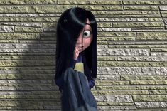 a cartoon character standing in front of a brick wall with her hand on her face