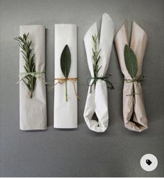 four napkins wrapped in white paper and tied with greenery