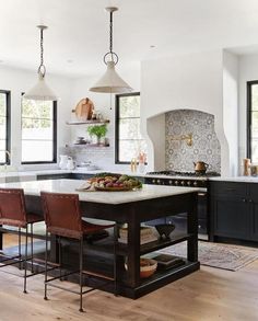 a kitchen with an island and chairs in the middle of it, surrounded by windows