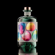 a glass bottle filled with colorful liquid on top of a table next to a black background