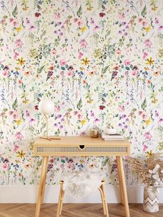 a desk with a flower wallpaper on the wall next to it and a lamp