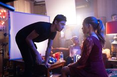 a young man and woman sitting in front of a projector screen while others look on