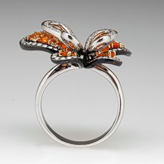 This exquisite butterfly ring is accented with seven (7), prong set, oval mixed cut natural spessartine garnet, two (2), prong set, round mixed cut natural spessartine garnet and one hundred forty-seven (147), bead/prong set, round brilliant cut diamonds. The ring measures 21.7mm at the top, rises 10.2mm above the finger, tapering to 3.5mm wide and 1.1mm thick at the base of the shank. This ring is currently a size 8.25. Luxury Butterfly Ring For Formal Occasions, Luxury Butterfly Ring With Brilliant Cut For Gift, Luxury Butterfly Ring With Brilliant Cut - Gift, Luxury Butterfly Ring With Brilliant Cut, Luxury Butterfly Ring For Wedding, Luxury Orange Jewelry With Gemstone Accents, Luxury Orange Gemstone Accented Jewelry, Luxury Orange Gemstone Jewelry, Diamond Butterfly Ring With Gemstone For Formal Occasions