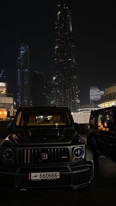 two cars parked in front of a city at night