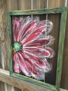 a painted flower in a wooden frame on a fence