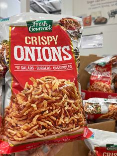 a person holding up a bag of crispy onions in front of some other bags