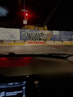 a car driving down a street at night with graffiti on the side of the road