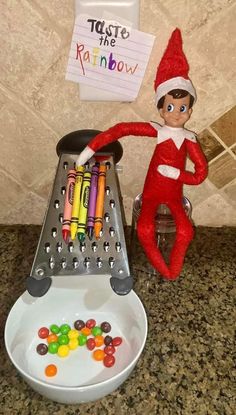 an elf with crayons in his hand next to a tray of candies