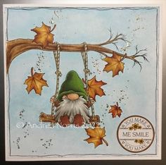 a card with an image of a gnome sitting on a swing in the fall leaves