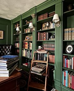 a room filled with lots of books on top of green bookcases next to a couch