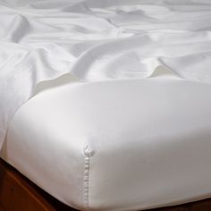 an unmade bed with white sheets and pillows