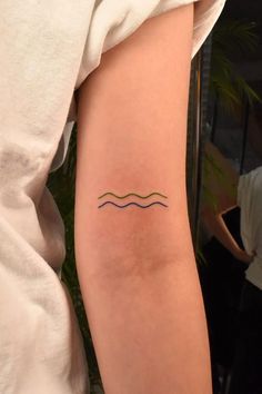 a woman's arm with a tattoo on it that has waves in the water