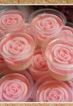 small cups filled with pink frosting sitting on top of a table next to flowers