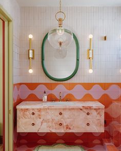 a bathroom with an oval mirror above the sink and colorful tile on the wall behind it