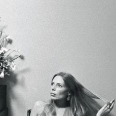 black and white photograph of woman sitting in chair with long hair blowing around her head