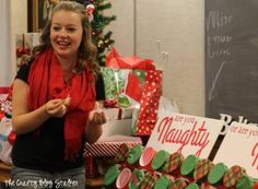 a woman standing next to a pile of christmas presents in front of a blackboard