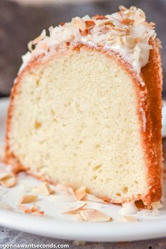 a piece of cake with white frosting and coconut on top is sitting on a plate