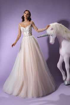 a woman in a wedding dress standing next to a white horse wearing a tiara