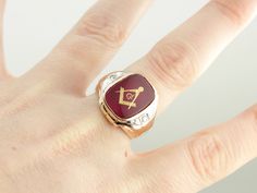 "This hefty, vintage Masonic ring is crafted from yellow gold and a bright ruby glass! The center is inlaid with a gold Masonic symbol. The shoulders of the ring feature bright diamonds, each set into a placard of white gold. The top has a great rectangular shape, and the stone really adds a pop of color! This is a boldly sized ring, perfect for a larger hand and a grander style! Metal: 10K Yellow Gold, White Gold Gem: Red Glass Gem Measurements: 15.6 x 12 mm, Rectangle Accents: 2 Diamonds total Masonic Symbol, Masonic Symbols, Handmade Stamps, Masonic Ring, Ring With Diamond, Glass Gems, Red Glass, Ruby Red, Eternity Bands