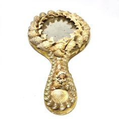 an ornate mirror with shells and pearls on it's sides, hanging from the wall