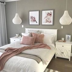 a white bed sitting in a bedroom next to two pictures on the wall above it