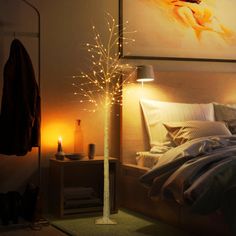 a bedroom with a lit up tree in the corner and a painting on the wall