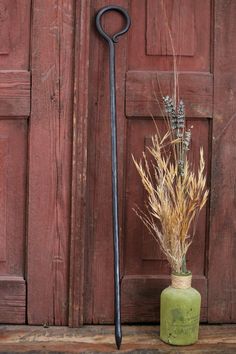 a plant in a green vase next to an old black shovel