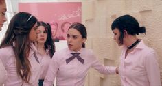 three women in pink shirts and ties standing next to each other with their hands together