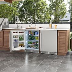 an open refrigerator in a kitchen next to a sink and counter with food on it