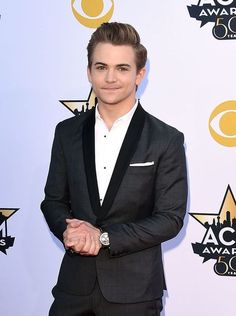 a young man in a tuxedo poses on the red carpet at an awards event