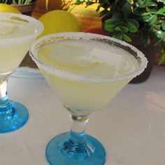 two martinis sitting next to each other on top of a white tablecloth covered table