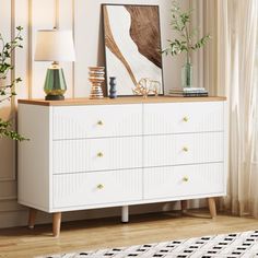 a white dresser sitting in a living room next to a window