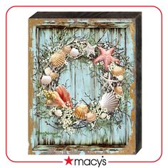 a wreath with seashells and starfish is hanging on a blue wooden door