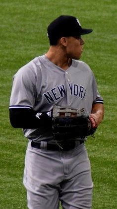 a baseball player holding a catchers mitt on top of a lush green field