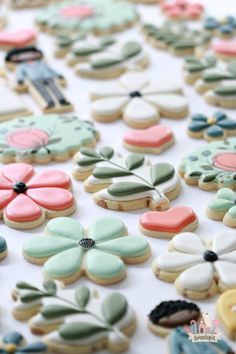 decorated cookies are arranged on a table with flowers and lady behind the cookie cutters