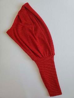 a red sweater laying on top of a white surface