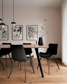 a dining room table with black chairs and pictures on the wall