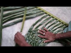 a person that is making something out of some kind of green leafy material on the floor