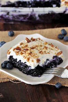 a piece of blueberry pie on a plate with a fork in front of it