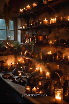 many lit candles are on shelves in a dark room with windows and potted plants