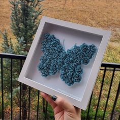 a person holding up a paper butterfly in a box