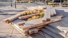 several wooden benches sitting on the side of a road next to grass and flowers in planters